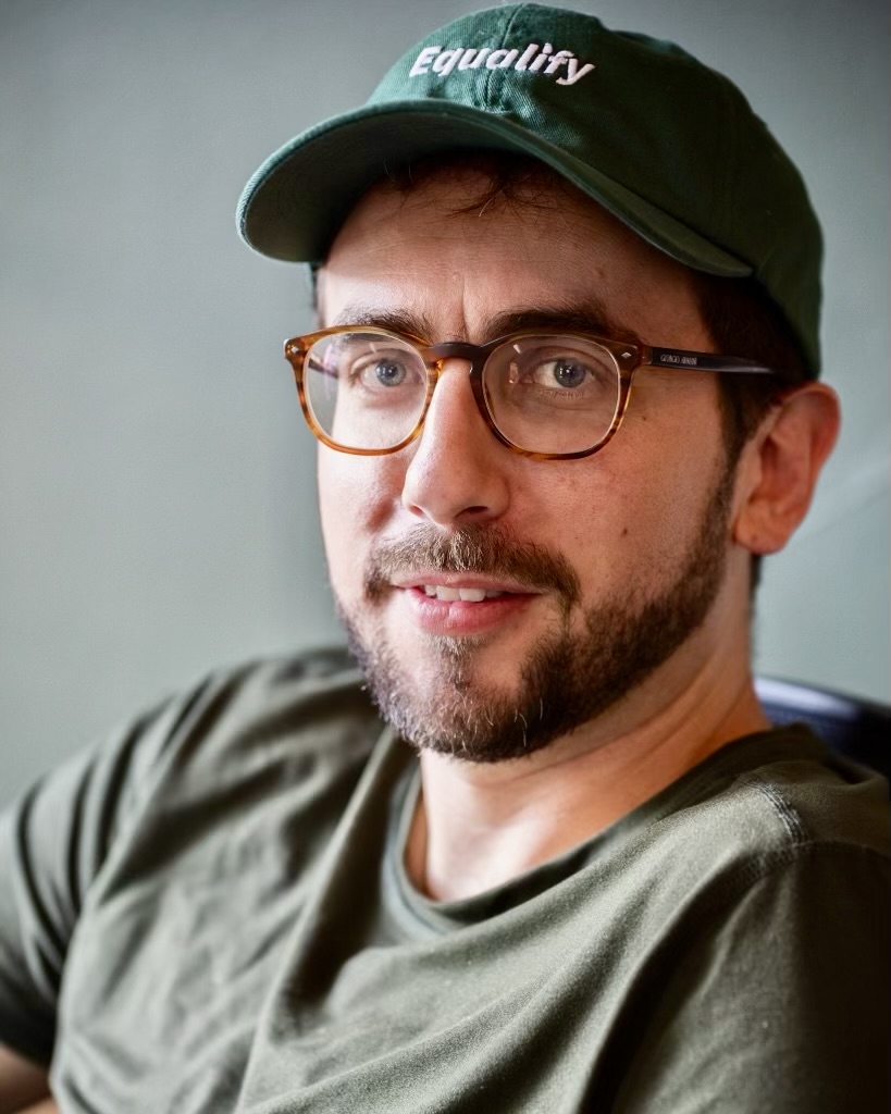 Headshot of Blake Bertuccelli-Booth, wearing a green Equalify hat.